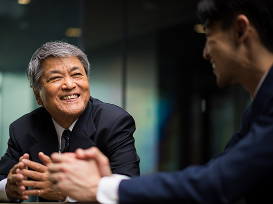 mature asian businessman talking to another person